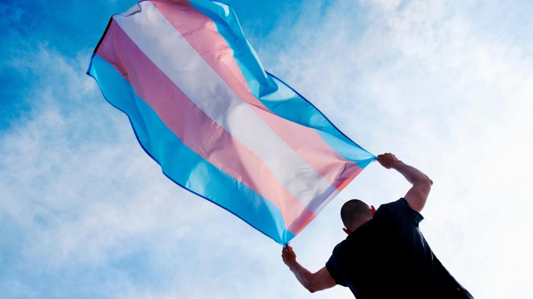 Osoba držící vlajku hrdosti trans lidí