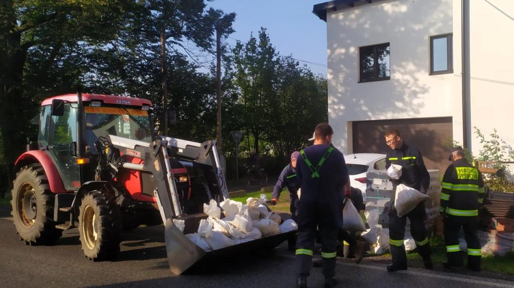 Starosta Višňové se svým týmem a hasiči odebírají od obyvatel pytle s pískem, které jim obec na ochranu nemovitostí zapůjčila