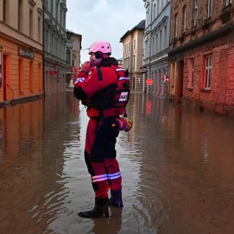 Hasič, záchranář v zatopené ulici poblíž rozvodněné řeky Opavy