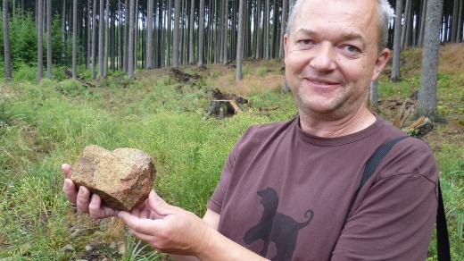 Červená barva kamene poukazuje na požár, archeolog Marek Krutiš ukazuje takový úlomek