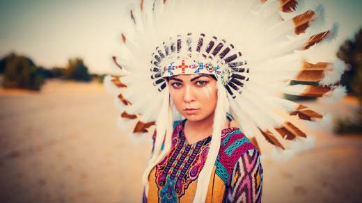 Mladá americká indiánka v tradičním kroji a čelence z peří divokých ptáků
