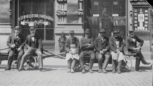 Muži sedící před obchodem J. Kleissla na rohu Sedláčkovy a Říšské (dnes Prešovské ulice) 1895