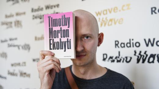 Ondřej Trhoň držící knihu Timothy Morton Ekobytí